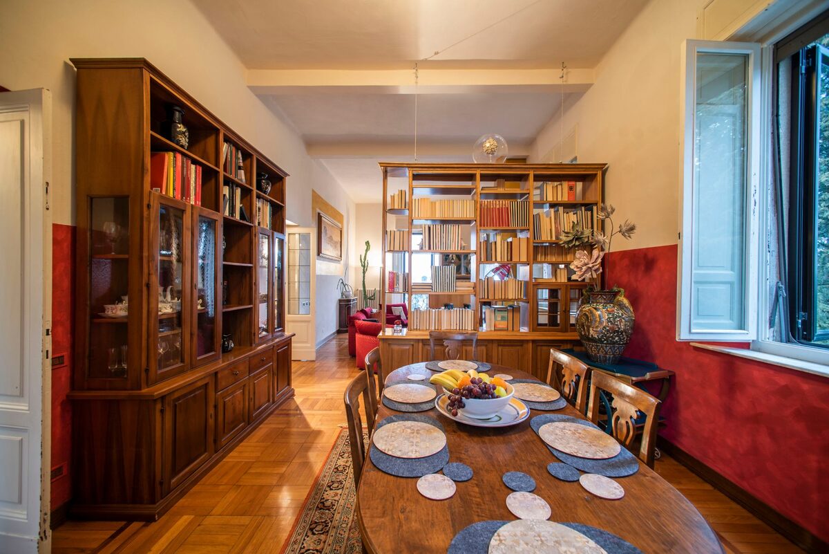 Sala da pranzo di Artemisia con libreria in legno e tavolo apparecchiato