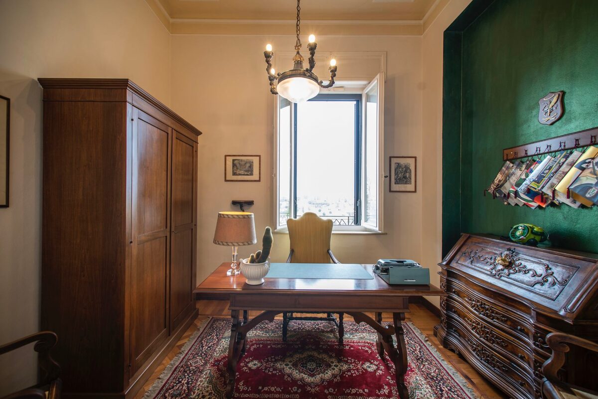 Studio dell’appartamento Artemisia con scrivania d’epoca, parete verde e lampadario