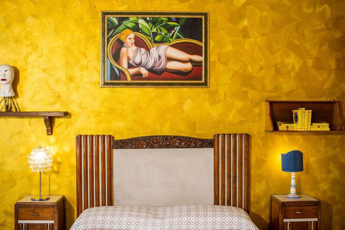 Camera da letto di Ipazia con parete gialla e quadro sopra la testata