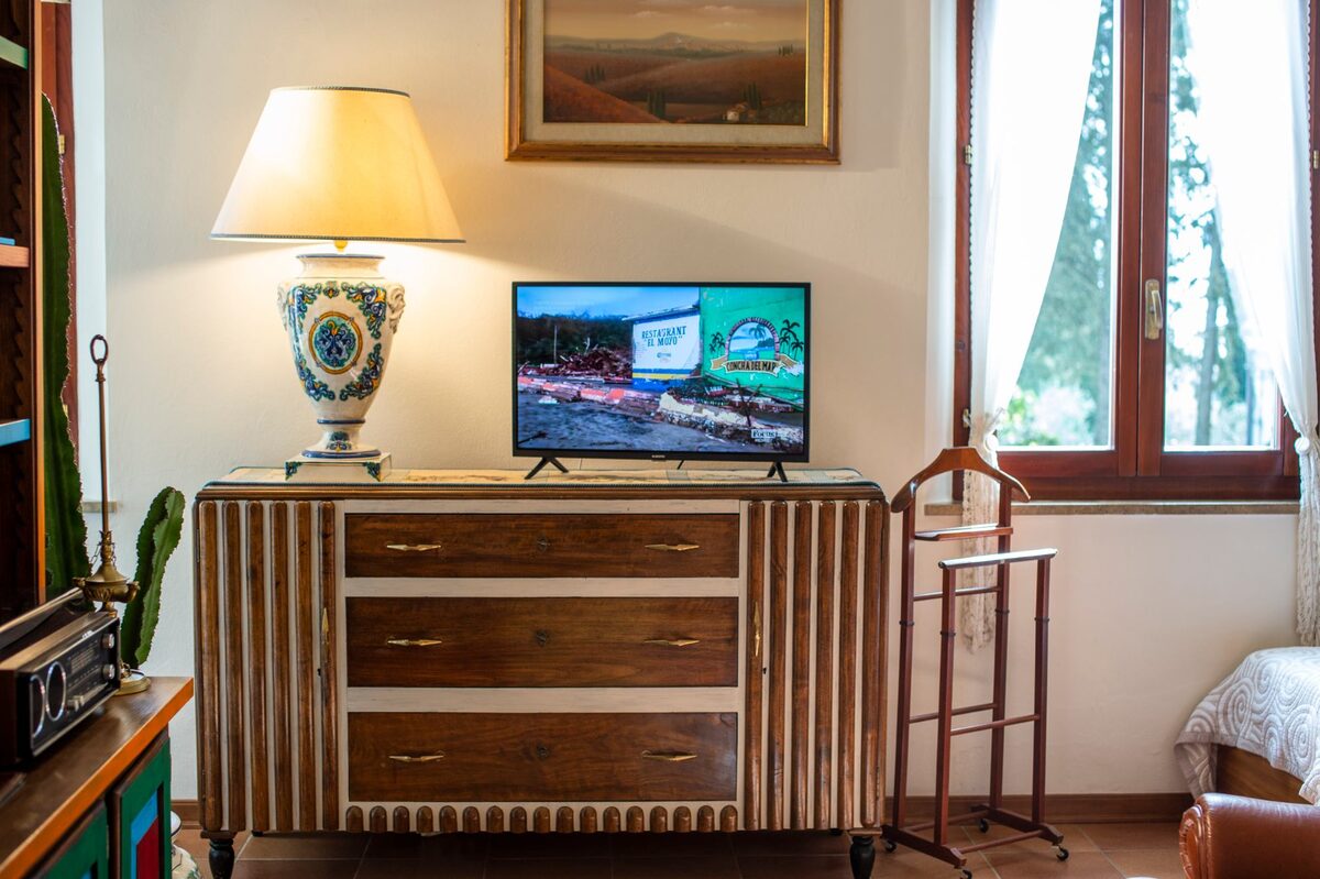 Soggiorno di Ipazia con credenza anni Trenta, smart TV e lampada d’epoca