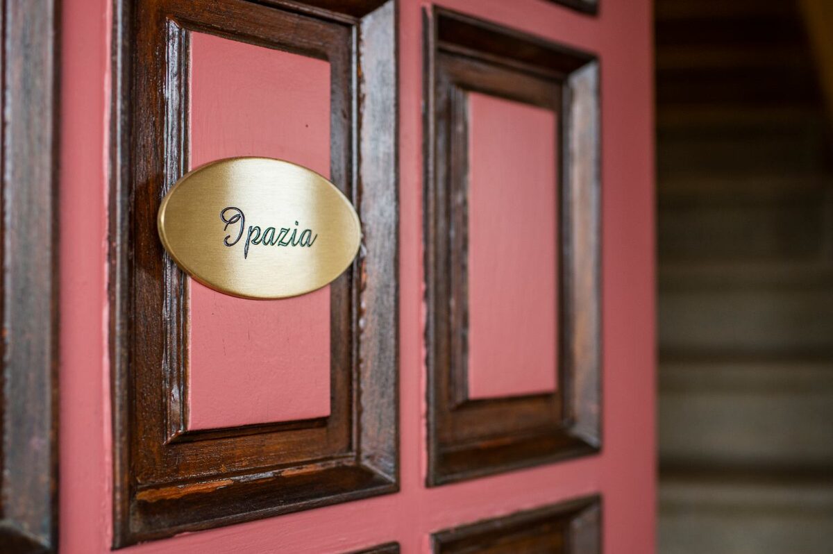 Targa in ottone con la scritta Ipazia sulla porta rosa del villino