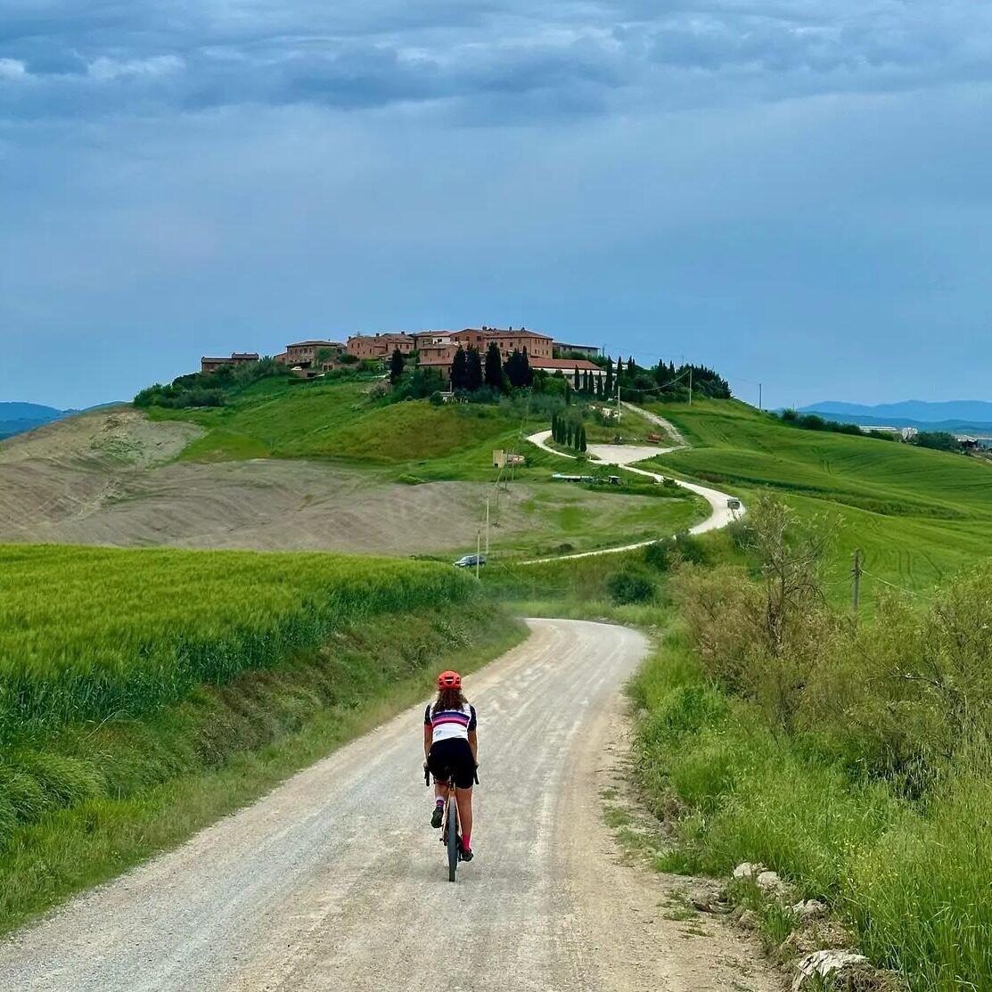 Ciclista su una strada bianca fra le colline toscane